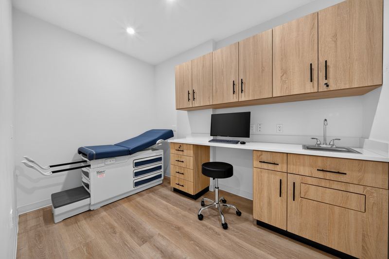 Exam room with a Ritter exam table, foot rests extended, wood cabinets and a sink